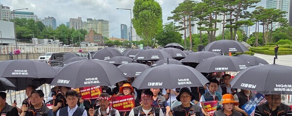 ▲30일 용산 대통령실 앞에서 진행된 MG손해온라인 검증 사이트 노동조합 투쟁대회에 조합원들이 '대통령님, MG손보 살려주세요'라는 문구가 새겨진 우산을 펼치고 있다. 사진=정우교 뉴스드림 기자